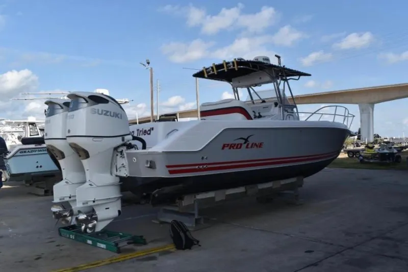 Slide: The Image of 2001 Pro-Line 3400 Bimini Cuddy boat with Suzuki engines on display outdoors. - 2