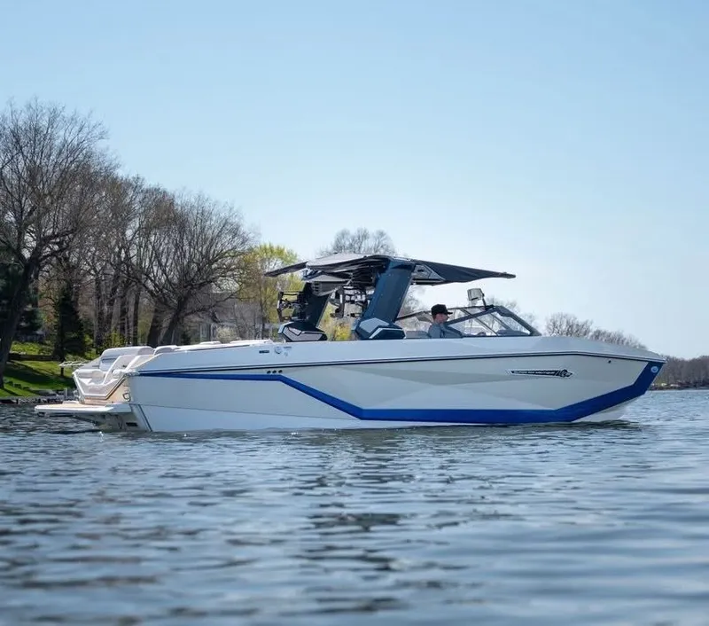 Slide: The Image of 2026 Nautique G25 boat on calm lake under clear sky. - 3