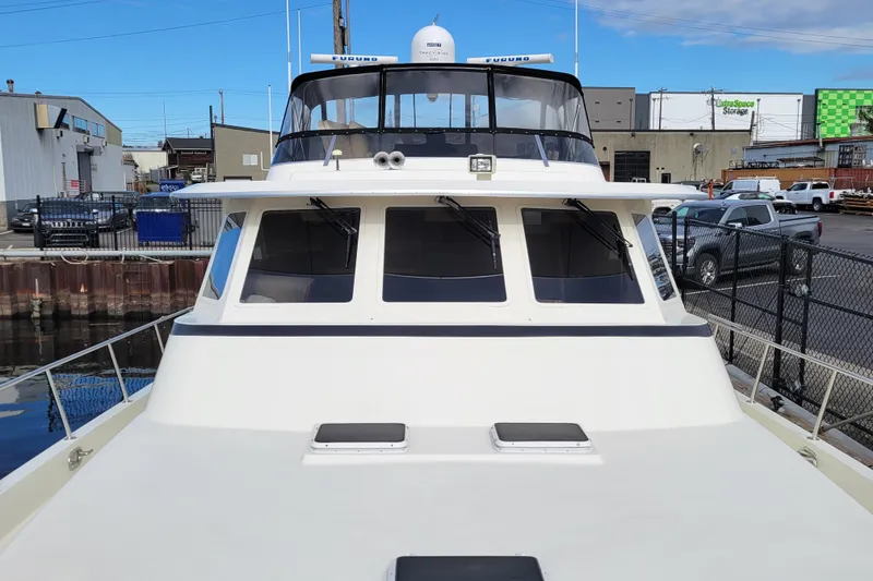 Slide: The Image of 1998 Tollycraft 65 Pilothouse yacht docked in an industrial marina setting. - 10