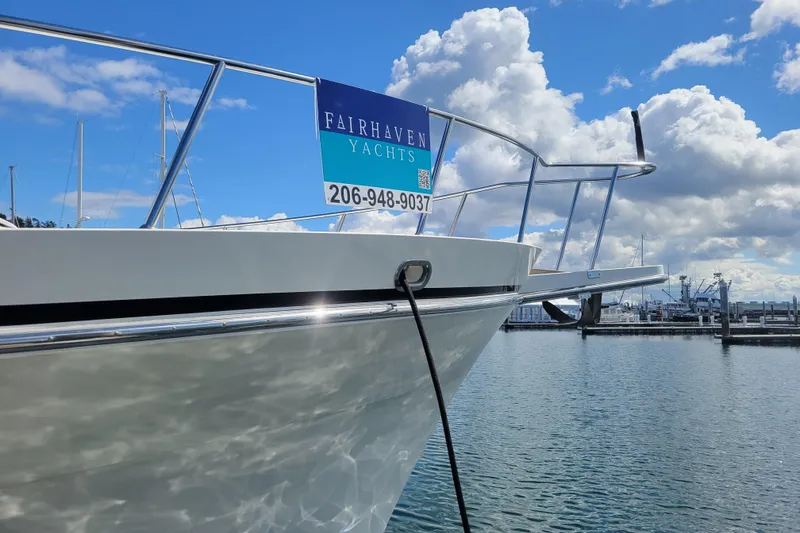 Slide: The Image of 1998 Tollycraft 65 Pilothouse yacht docked with Fairhaven Yachts sign, under a partly cloudy sky. - 13