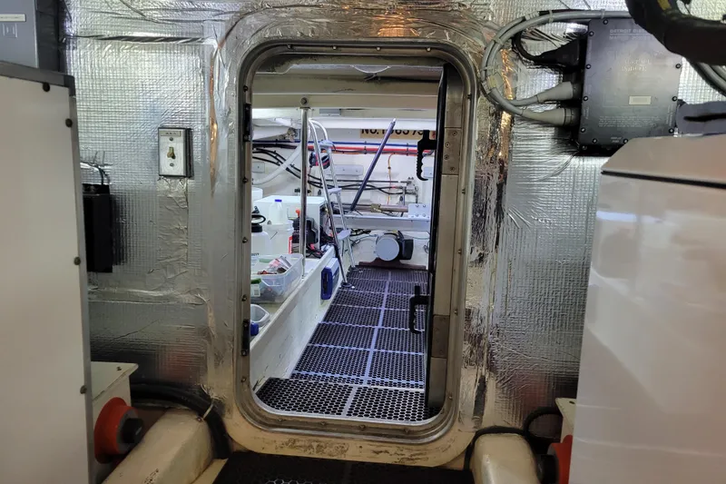 Slide: The Image of Engine room of a 1998 Tollycraft 65 Pilothouse yacht, featuring metallic insulation and equipment. - 72