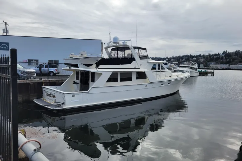 Slide: The Image of 1998 Tollycraft 65 Pilothouse yacht docked in a marina under cloudy skies. - 79
