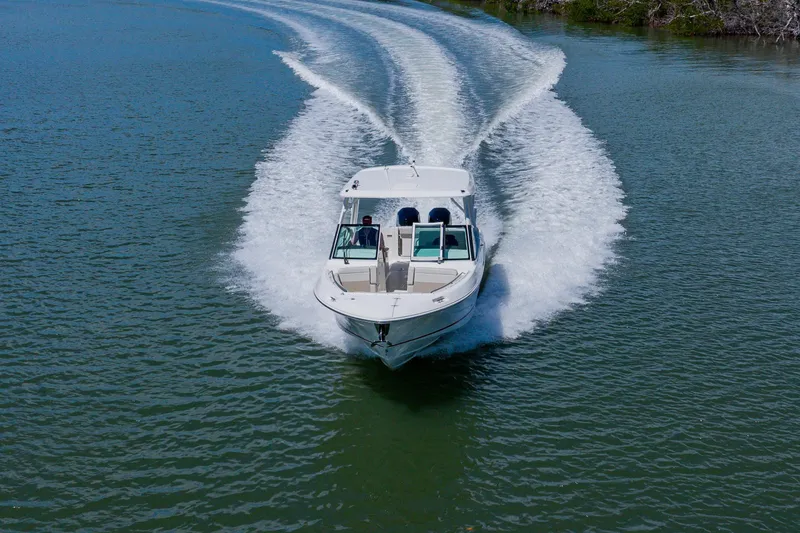 Slide: The Image of 2021 Boston Whaler 280 Vantage cruising on a serene waterway, creating a dynamic wake. - 18
