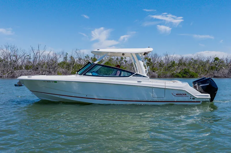 Slide: The Image of 2021 Boston Whaler 280 Vantage boat cruising on a sunny day, surrounded by lush greenery. - 2