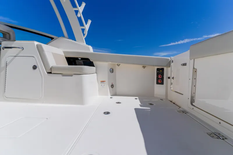 Slide: The Image of 2021 Boston Whaler 280 Vantage boat interior with seating and storage, under clear blue sky. - 32