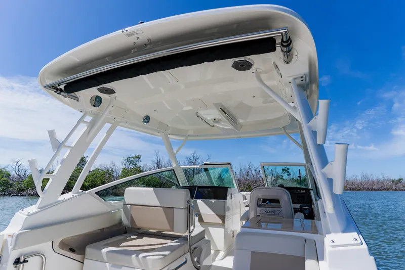 Slide: The Image of 2021 Boston Whaler 280 Vantage boat interior with seating and canopy, under clear blue sky. - 44