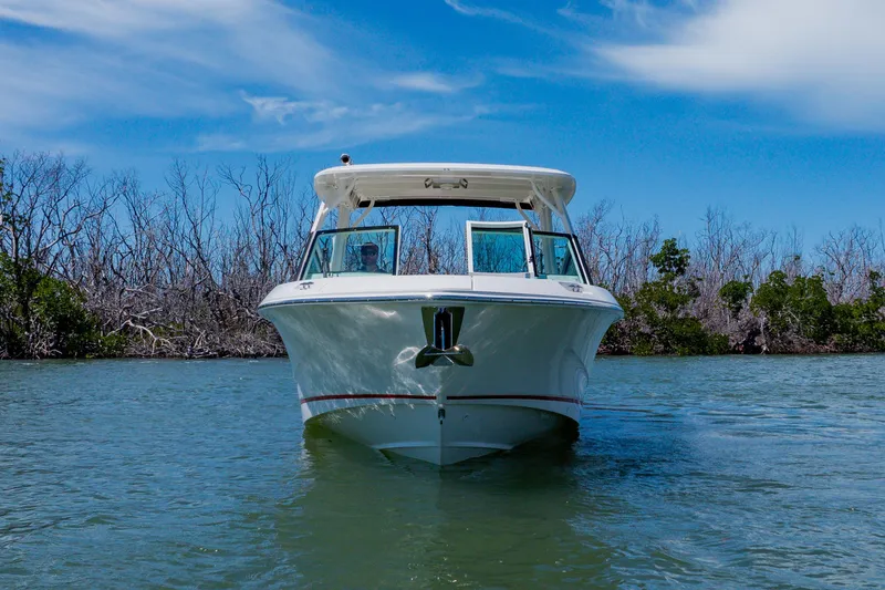 Slide: The Image of 2021 Boston Whaler 280 Vantage boat cruising on a serene waterway under a clear blue sky. - 7