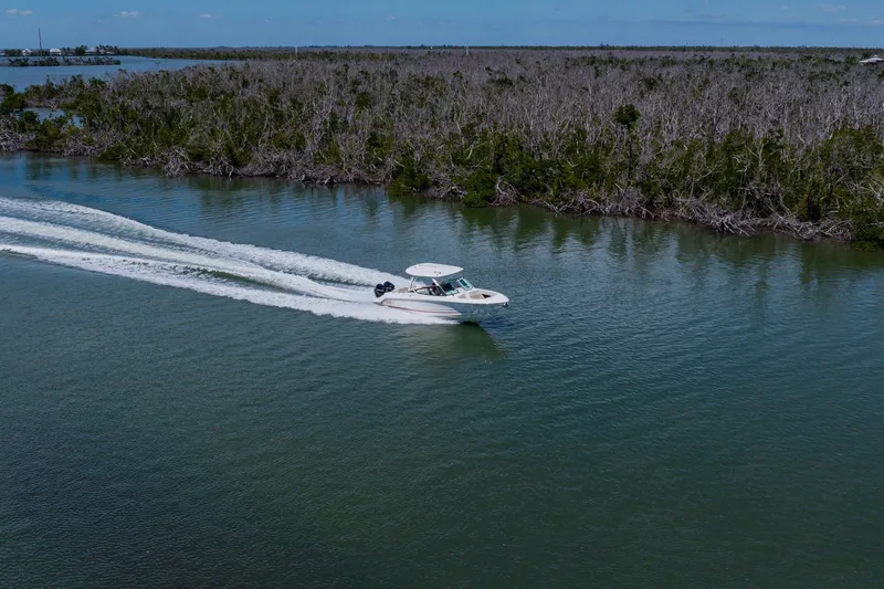 Slide: The Image of 2021 Boston Whaler 280 Vantage cruising on a serene river with lush forest backdrop. - 85