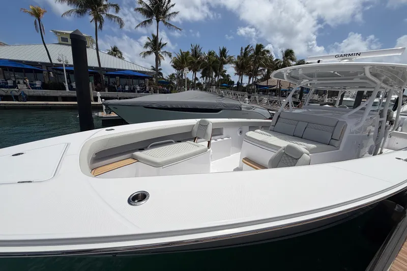 Slide: The Image of 2026 Jupiter 43 boat docked at marina with triple outboard engines, palm trees, and blue sky. - 4