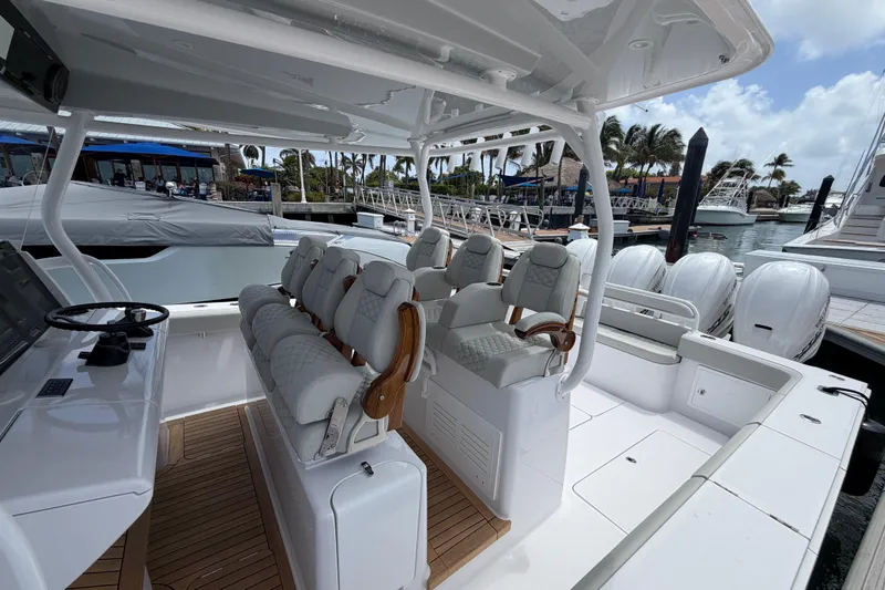 Slide: The Image of 2026 Jupiter 43 boat with luxurious seating, docked under a sunny sky with palm trees. - 7