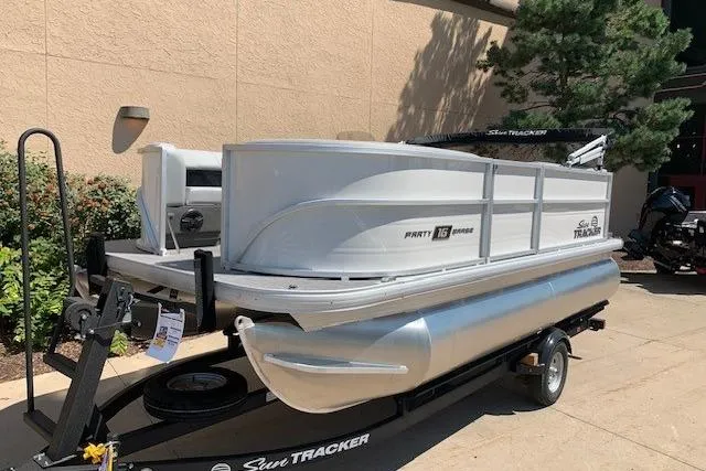 Slide: The Image of 2026 Sun Tracker Party Barge 16 DLX pontoon boat on trailer, parked outdoors. - 23