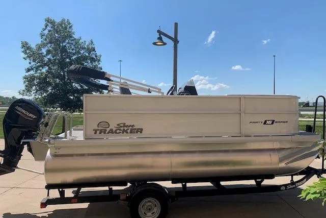 Slide: The Image of 2026 Sun Tracker Party Barge 16 DLX pontoon boat on trailer, parked outdoors. - 20