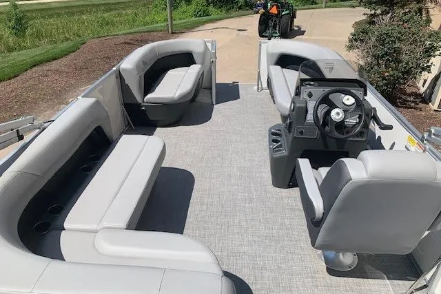 Slide: The Image of 2026 Sun Tracker Party Barge 16 DLX interior with gray seating and steering console. - 28