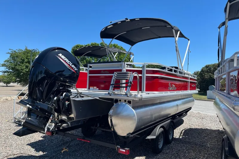 Slide: The Image of 2026 Sun Tracker Fishin' Barge 22 DLX pontoon boat with Mercury engine, parked outdoors. - 2