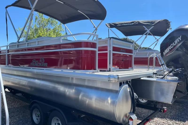 Slide: The Image of 2026 Sun Tracker Fishin' Barge 22 DLX pontoon boat with Mercury engine, parked outdoors. - 3
