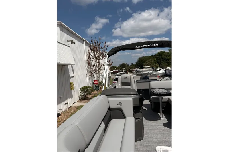 Slide: The Image of 2026 Sun Tracker SportFish 20 DLX pontoon boat with gray seating, docked outdoors. - 100