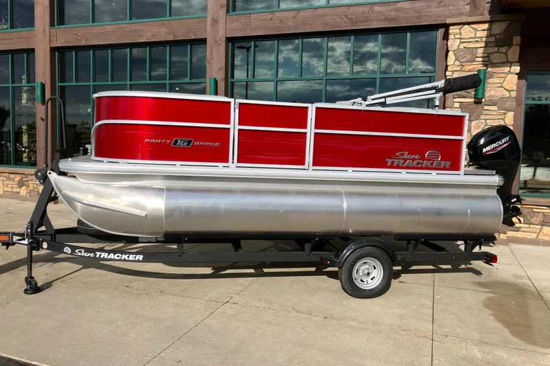 The Image of 2026 Sun Tracker Party Barge 16 DLX pontoon boat on trailer, red and silver design. - 0