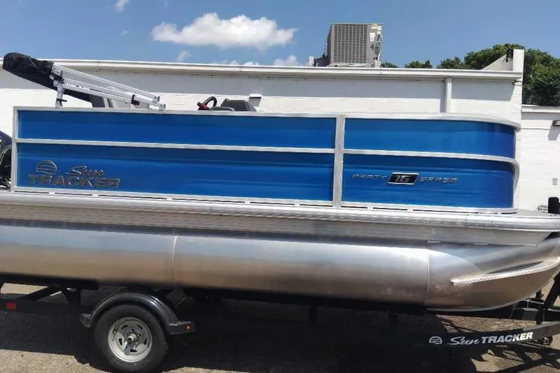 Slide: The Image of 2026 Sun Tracker Party Barge 16 DLX pontoon boat with blue exterior on trailer. - 2