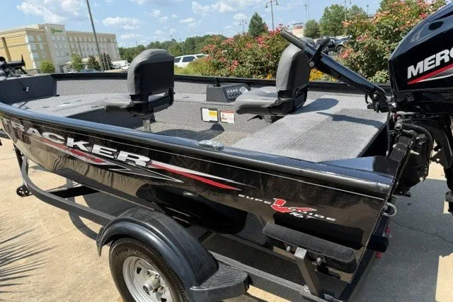Slide: The Image of 2025 Tracker Super Guide V-16 T boat with Mercury engine, parked outdoors on a sunny day. - 2