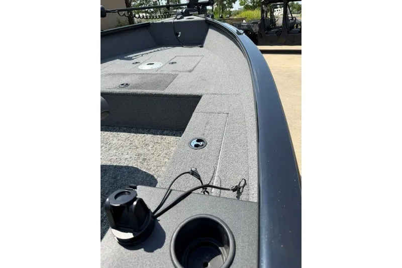 Slide: The Image of 2025 Tracker Super Guide V-16 T boat interior with gray carpet and fishing rod holders. - 9