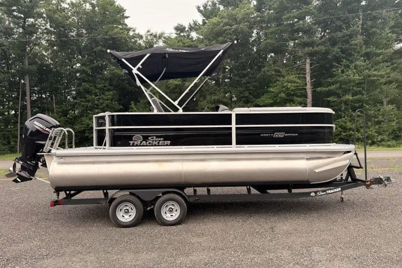 Slide: The Image of 2026 Sun Tracker Party Barge 20 DLX pontoon boat on trailer, parked outdoors. - 2