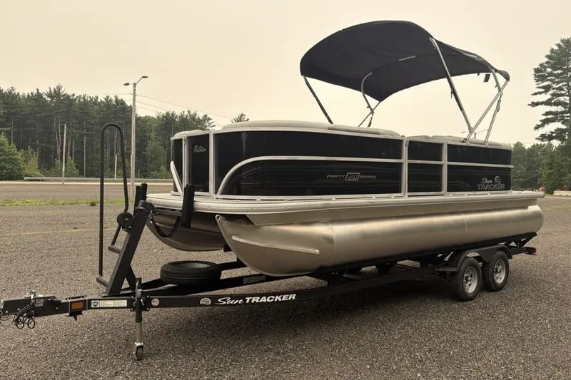 Slide: The Image of 2026 Sun Tracker Party Barge 20 DLX pontoon boat on trailer, parked outdoors. - 1