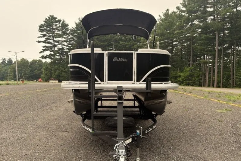 Slide: The Image of 2026 Sun Tracker Party Barge 20 DLX pontoon boat on trailer, surrounded by trees. - 6