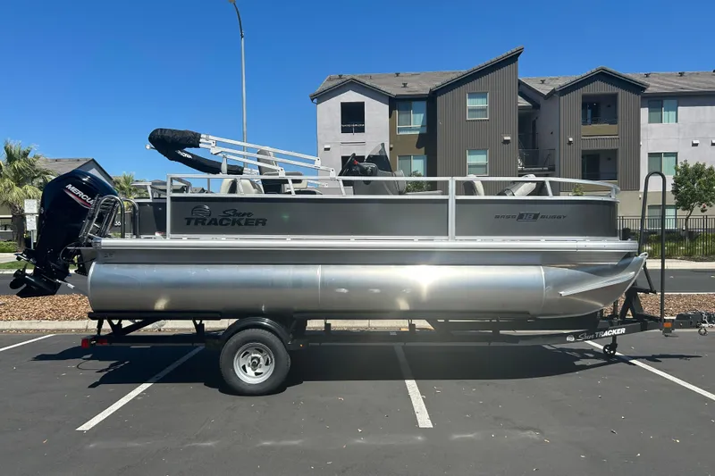 The Image of 2026 Sun Tracker Bass Buggy 18 DLX pontoon boat parked in urban setting. - 0