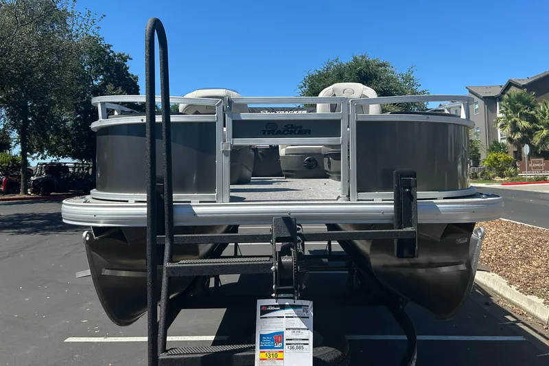 Slide: The Image of 2026 Sun Tracker Bass Buggy 18 DLX pontoon boat displayed in a parking lot. - 4