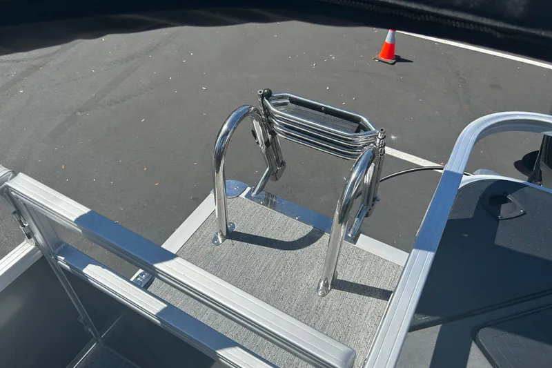 Slide: The Image of 2026 Sun Tracker Bass Buggy 18 DLX boat ladder on deck, parked on asphalt. - 28