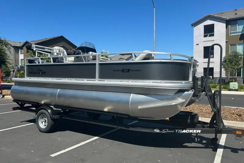 Slide: The Image of 2026 Sun Tracker Bass Buggy 18 DLX pontoon boat on trailer in parking lot. - 2