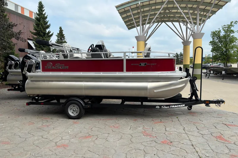 The Image of 2026 Sun Tracker Bass Buggy 16 XL Select pontoon boat on trailer, outdoor display. - 0