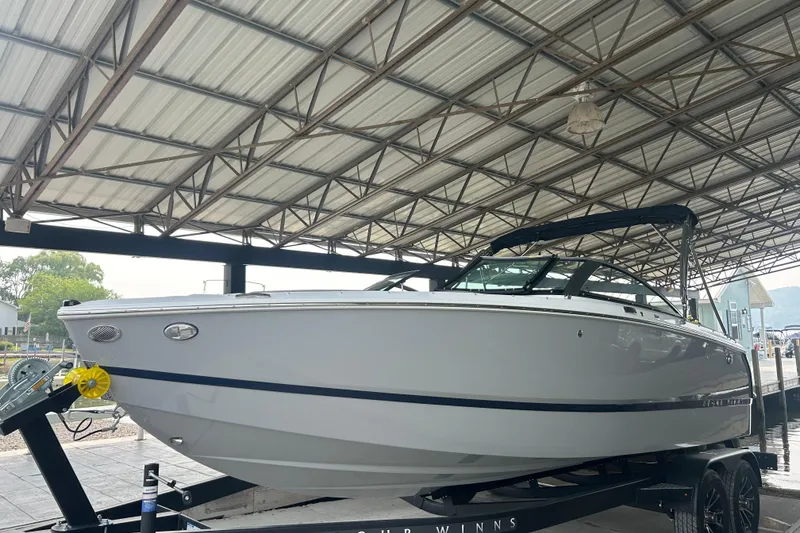 Slide: The Image of 2025 Four Winns H2 boat under a metal canopy on a trailer. - 2