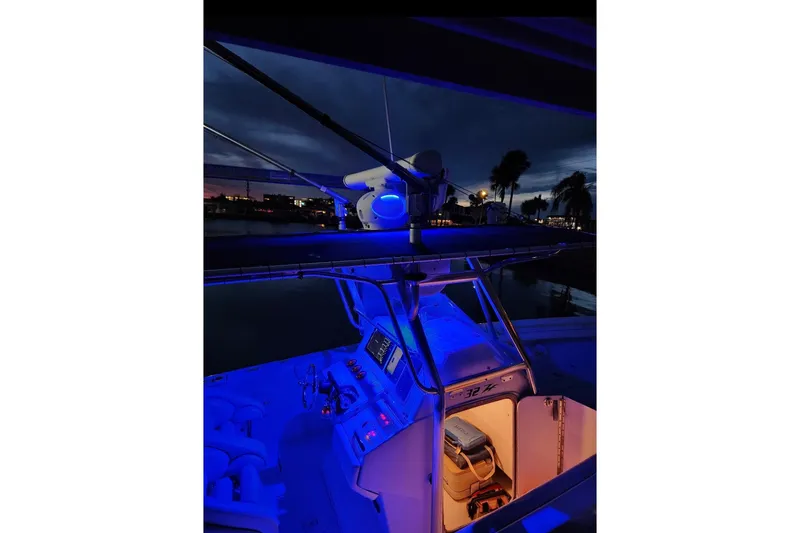 Slide: The Image of 2003 Donzi 32 ZF Open boat illuminated with blue lights at dusk, showcasing cockpit and cabin. - 33