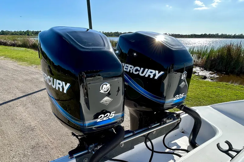 Slide: The Image of Twin Mercury 225 outboard engines on a 2003 Donzi 32 ZF Open boat by a lake. - 6