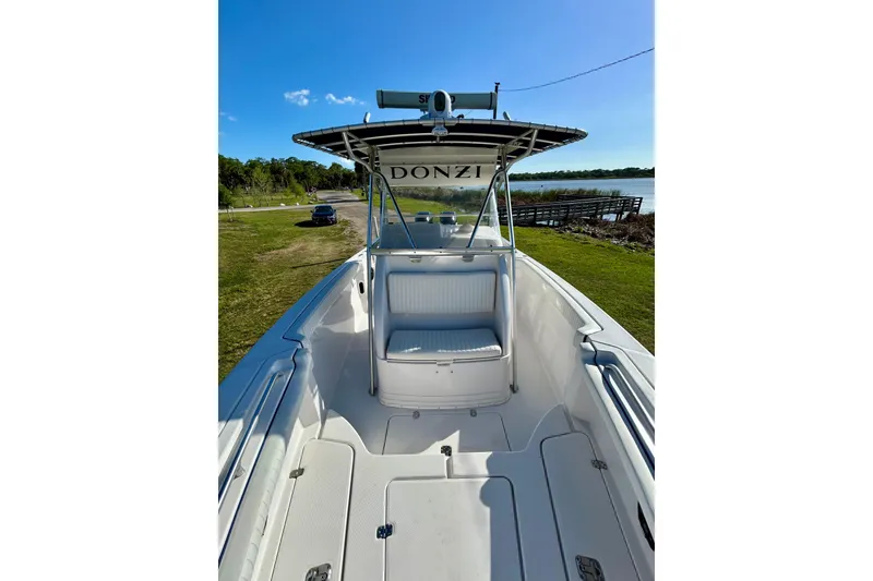 Slide: The Image of 2003 Donzi 32 ZF Open boat with seating, docked near a scenic lake. - 9