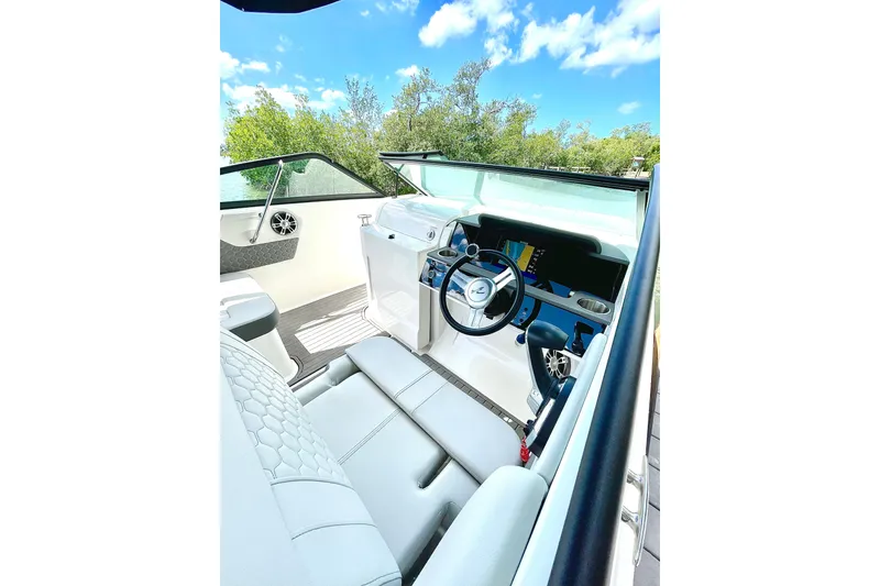 Slide: The Image of 2024 Sea Ray SDX 250 Outboard cockpit with modern steering and dashboard, under a clear blue sky. - 12