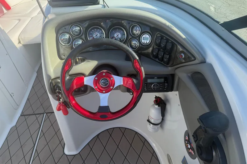 Slide: The Image of Cockpit of 2005 Crownline 270 BR boat with red steering wheel and control panel. - 12