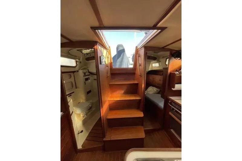 Slide: The Image of Interior view of 1990 Sabre 38 sailboat, featuring wooden stairs and cozy cabin layout. - 9
