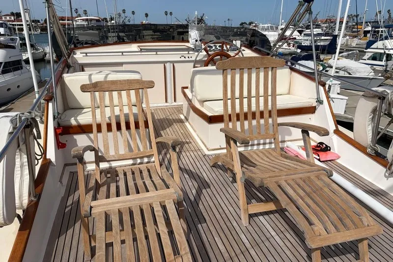 Slide: The Image of 1979 Grand Banks 42 Europa yacht deck with wooden chairs and marina view. - 12