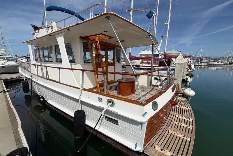 Slide: The Image of 1979 Grand Banks 42 Europa docked at marina, showcasing classic design and wooden accents. - 2