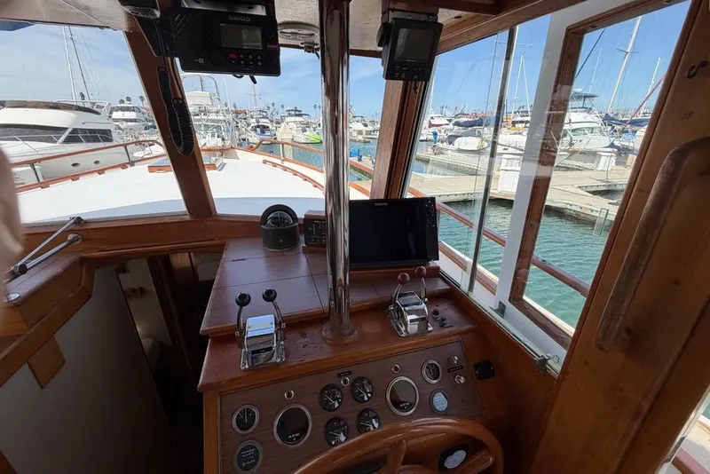 Slide: The Image of 1979 Grand Banks 42 Europa helm with wooden dashboard, marina view, and navigational instruments. - 29