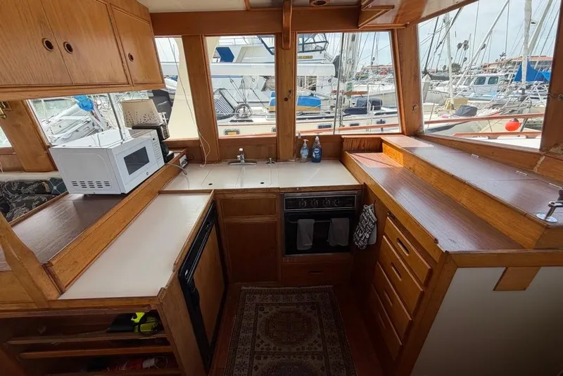 Slide: The Image of 1979 Grand Banks 42 Europa yacht kitchen with wooden cabinetry, microwave, and marina view. - 32