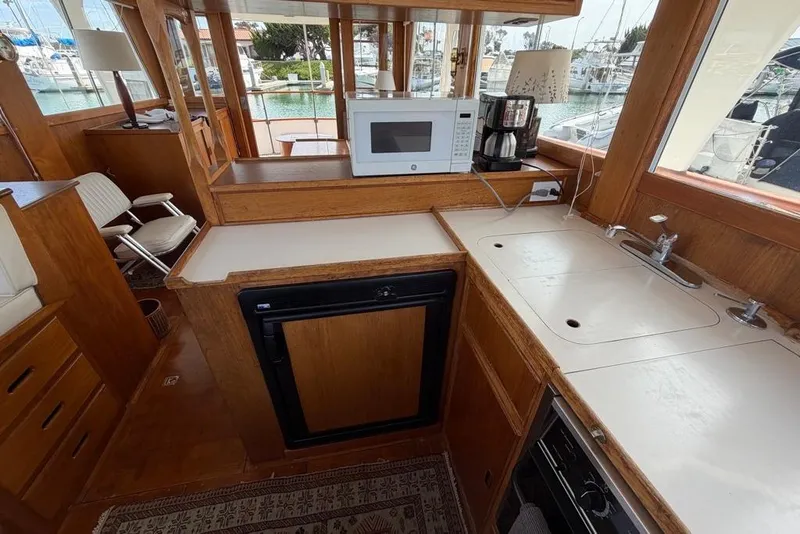 Slide: The Image of 1979 Grand Banks 42 Europa yacht interior with kitchen, featuring microwave, sink, and wooden cabinetry. - 33