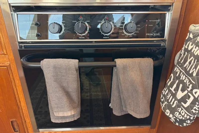 Slide: The Image of Oven controls on a 1979 Grand Banks 42 Europa yacht, featuring towels and a mitt. - 34