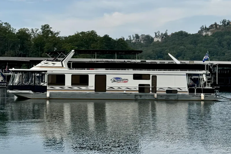 The Image of 1998 Sumerset 16x76 houseboat on a calm lake with wooded shoreline. - 0