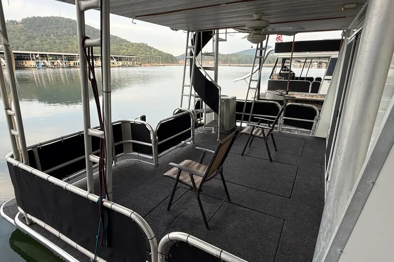 Slide: The Image of 1998 Sumerset 16x76 houseboat deck with chairs, overlooking serene lake and marina. - 14