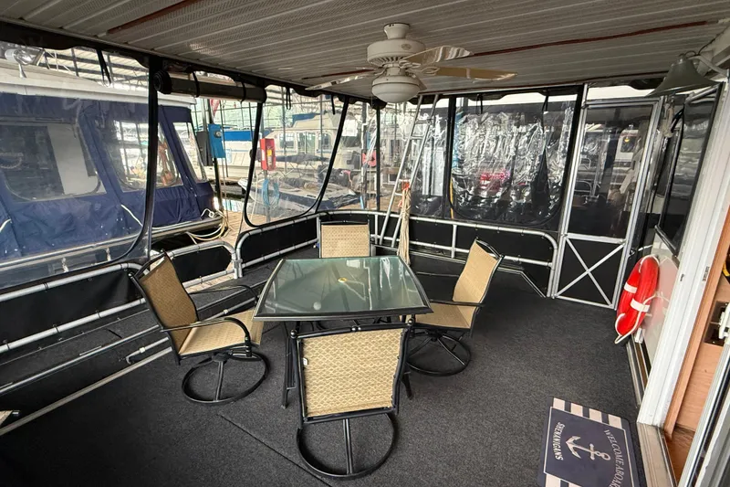 Slide: The Image of Outdoor seating area on a 1998 Sumerset 16x76 houseboat with glass table and chairs. - 2