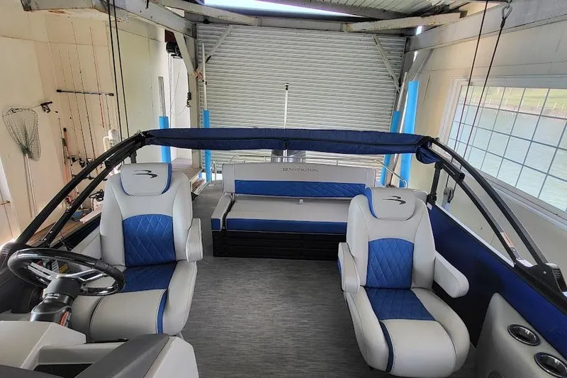 Slide: The Image of 2023 Bennington L 25 Swingback interior with blue and white seating, docked in a boathouse. - 15