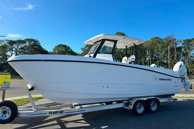 The Image of 2026 Twin Vee 260 GFX2 CC boat on trailer, parked outdoors under clear blue sky. - 0